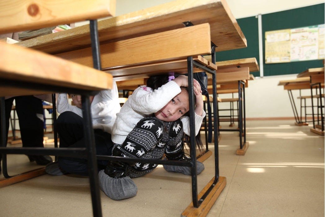 School children take cover under a desk during an earthquake preparedness drill | Photo:&nbsp;IFRC